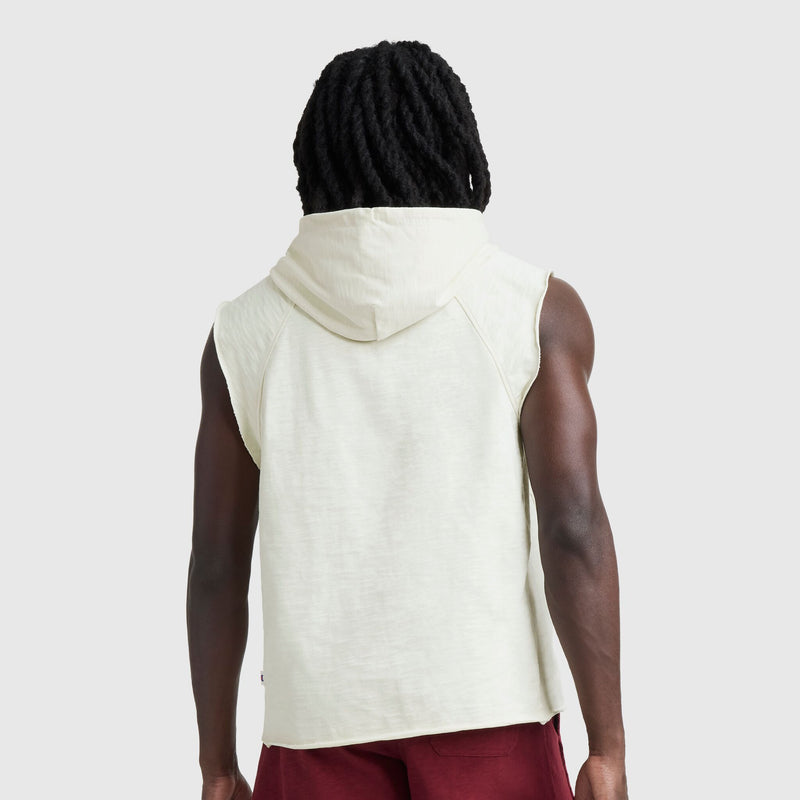 A person with long, black, twisted hair is seen from behind wearing the Champion Modern Retro Washed Sleeveless Hoodie with C Logo and red shorts against a plain gray background.
