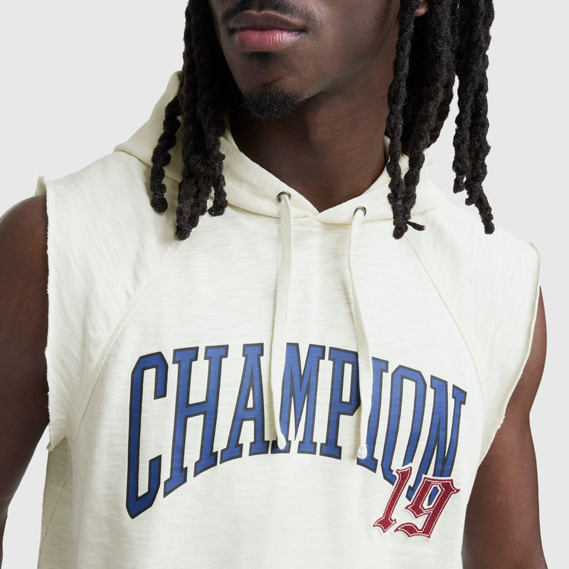 A person with long, dark dreadlocks wears a light-colored Champion Modern Retro Washed Sleeveless Hoodie featuring bold blue CHAMPION lettering and a red 19 patch, with a plain neutral background.