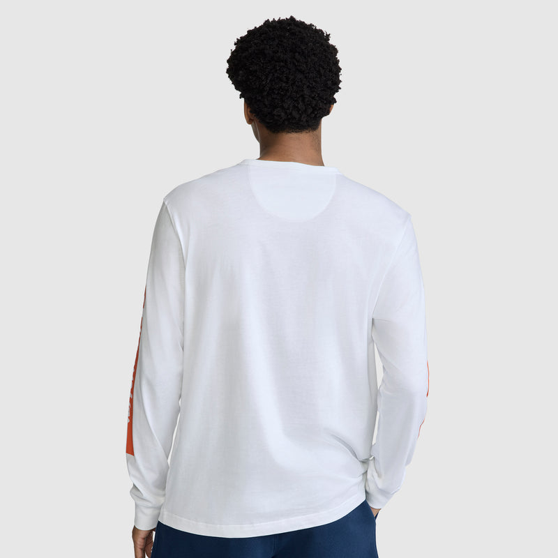 A person with short curly hair is wearing the Champion Medallion Long Sleeve Graphic T-Shirt and dark pants, standing with their back to the camera against a plain light gray background.