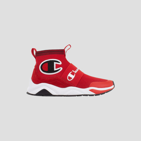 The Champion Men's Rally Pro is a red, sock-style high-top sneaker with a white sole, black and white accents, mesh fabric, pull tab, large black and white C logo on the ankle, and the brand name across the strap.