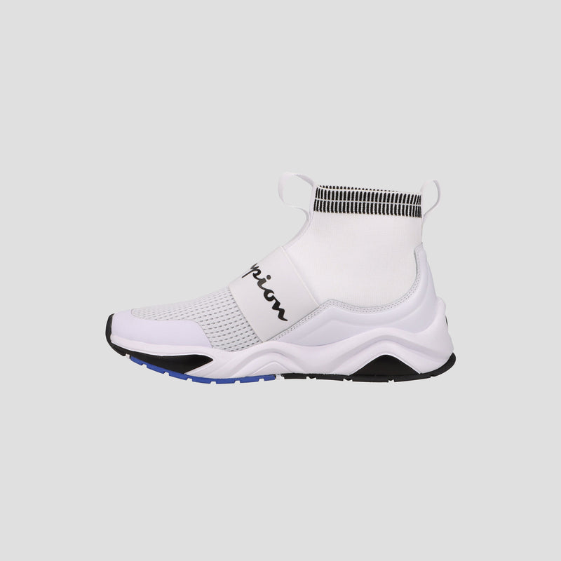 The Champion Men's Rally Pro sneaker in white features a sock-style ankle, slip-on design, black side branding, and a chunky sole with black and blue accents, shown on a plain gray background.