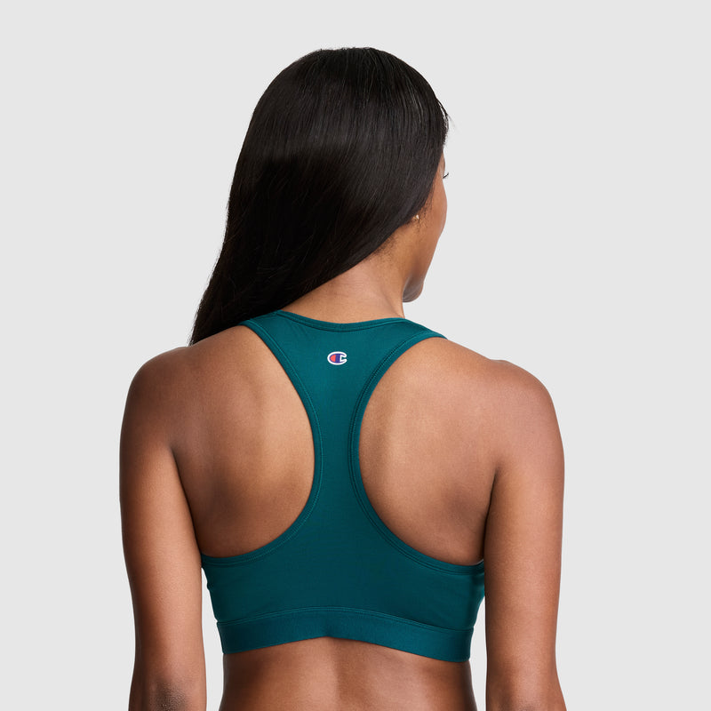 A woman with long dark hair is shown from the back wearing the Champion Compression Sports Bra, C Logo—a teal racerback women’s bra designed for moderate support with moisture-wicking fabric—standing out against a plain light gray background.