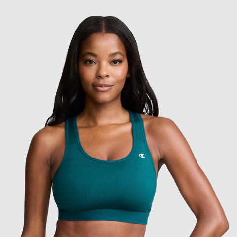 A woman with long dark hair wears the Champion Compression Sports Bra, featuring moderate support and the C Logo in teal, as she looks confidently at the camera against a plain light gray background.