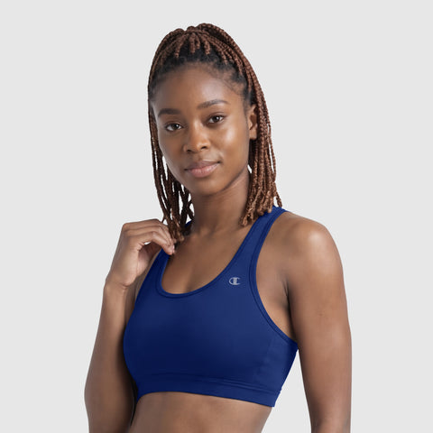 A woman with braided hair wears the Champion Compression Sports Bra, C Logo in blue and looks confidently at the camera against a plain light background.