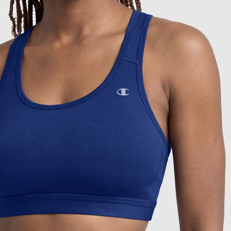 A person wearing a blue Champion Compression Sports Bra with a small C logo on the left side, offering moderate support, shown from shoulders to mid-torso against a plain background.
