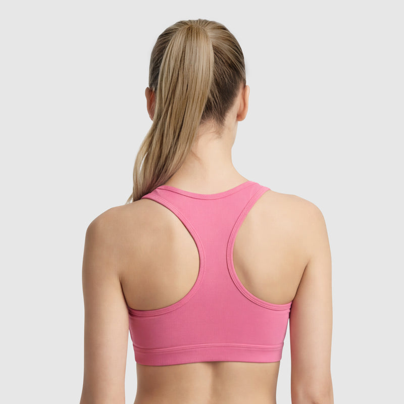 A woman with long blonde hair in a ponytail is shown from the back wearing the Champion Compression Sports Bra, C Logo, in pink against a plain light gray background.