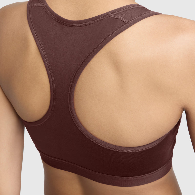 A person is shown from the back wearing the Champion Compression Sports Bra, C Logo in brown, highlighting its moisture-wicking fabric and supportive athletic cut designed for moderate support.