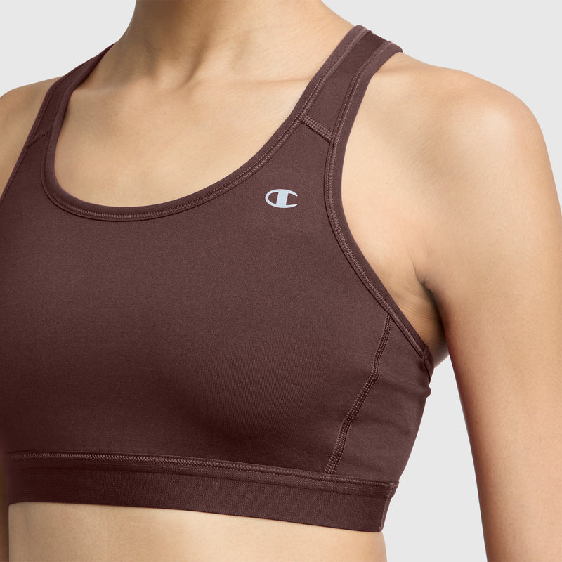 A person wearing the Champion Compression Sports Bra featuring a small C logo on the left chest, designed for moderate support and moisture-wicking comfort, is photographed from the shoulders to the midriff against a plain background.