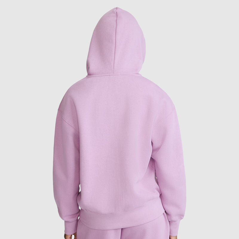 A person is shown from the back, wearing a light purple Champion Powerblend Fleece Zip-Up Hoodie, C Logo, along with matching pants, standing against a plain white background.