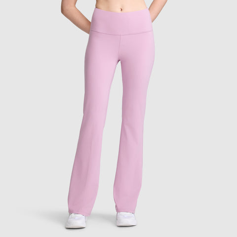 A person wearing Champion Soft Touch Flare Leggings (Anti Odor, C Logo) in high-waisted light pink—perfect workout leggings for women—and white sneakers stands against a plain light gray background, with their hands behind their back.