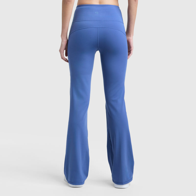 A person is shown from the back wearing Champion Soft Touch Flare Leggings with a wide waistband and C Logo, featuring anti-odor technology, paired with white shoes, standing against a plain white background.