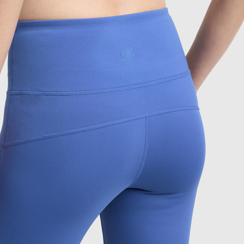 Close-up of a person wearing Champion Soft Touch Flare Leggings, featuring a high-waisted, wide waistband; smooth, stretchy, moisture-wicking material with anti-odor tech and C logo. Shot shows waistband and upper leg area from the back.