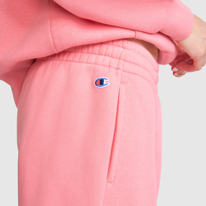 A person is shown from the side wearing Champion’s Powerblend Oversized Sweatpants with the signature C Logo, paired with a matching sweatshirt. Crafted from soft Powerblend fleece fabric, these sweatpants feature the Champion logo above the pocket. The hand rests near the waistband of the oversized fit, set against a plain, light-colored background.