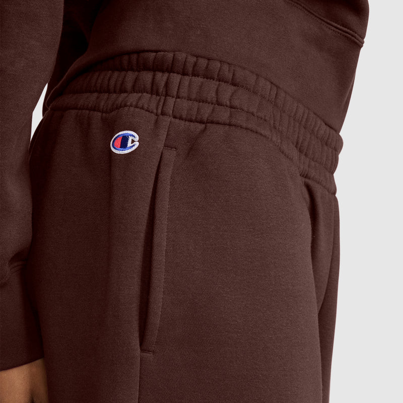 Close-up of a person wearing Champion’s Powerblend Oversized Sweatpants, featuring an elastic waistband, side pocket, and an embroidered C logo on the hip.