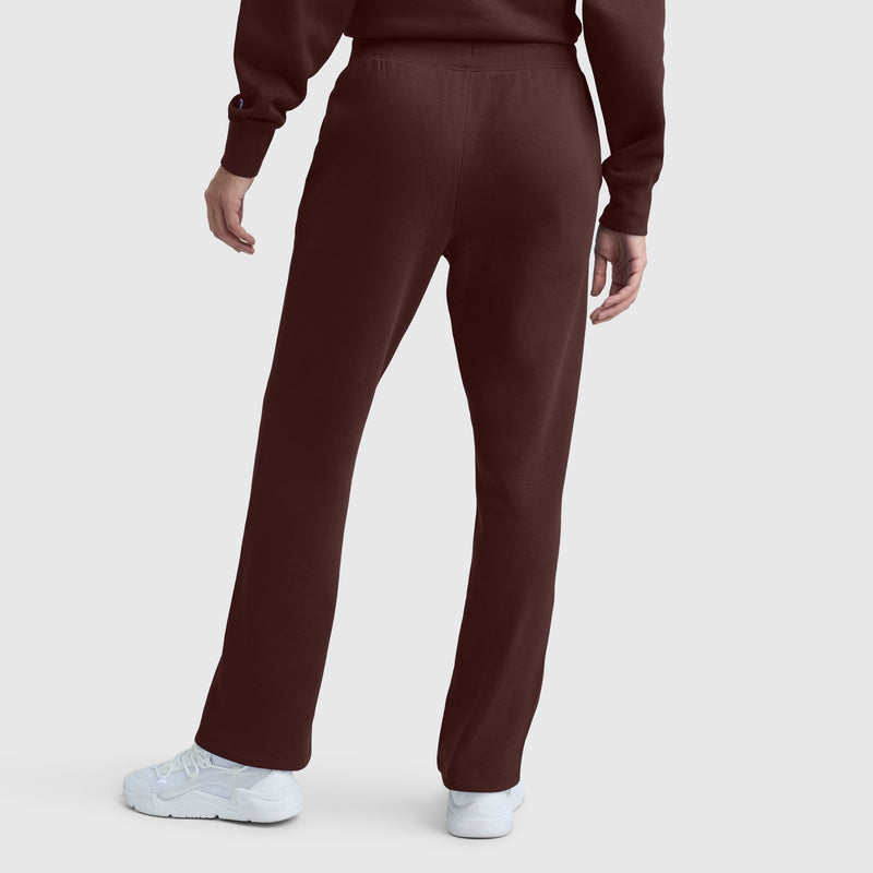 A person stands facing away, wearing brown Champion Powerblend Straight Hem Sweatpants paired with a matching midweight fleece sweatshirt and white sneakers, set against a plain light background.