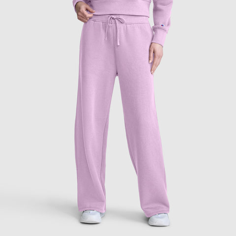 A person is wearing Champion Wide Leg Fleece Sweatpants with a C Logo in light purple, paired with a matching sweatshirt and white sneakers, standing against a plain gray background.