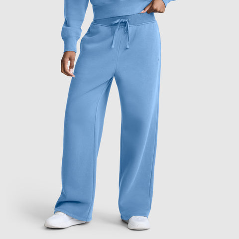 A person is wearing Champion Wide Leg Fleece Sweatpants with C Logo in light blue, paired with a matching sweatshirt and white sneakers, standing against a plain light background.
