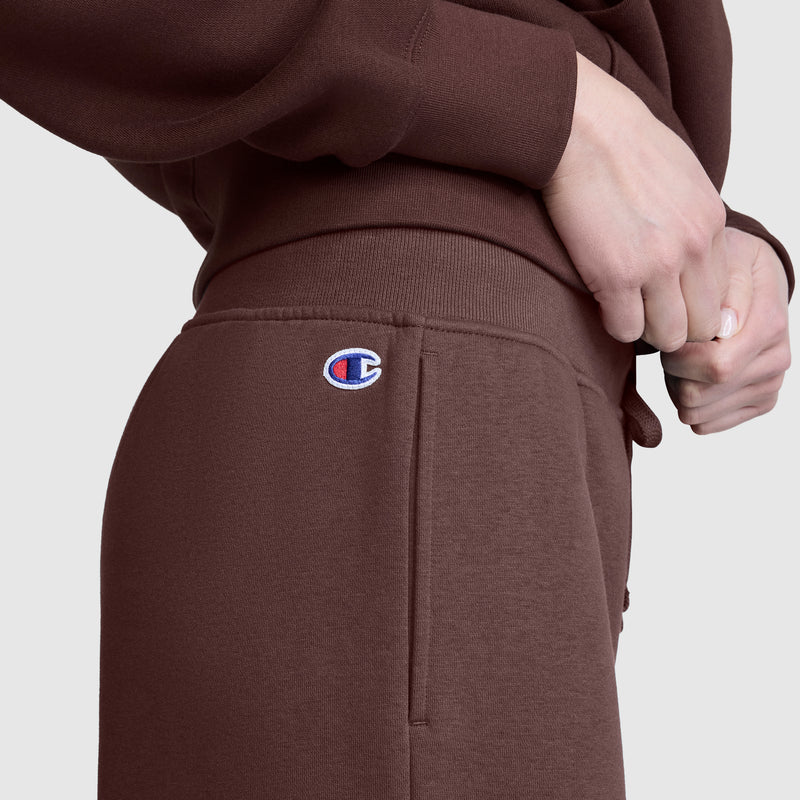 A person is wearing brown Champion Wide Leg Fleece Sweatpants, featuring the C Logo, paired with a matching brown sweatshirt. With hands resting near the waistband, only the torso and upper legs are visible, highlighting the comfort of these women’s cotton fleece pants by Champion.