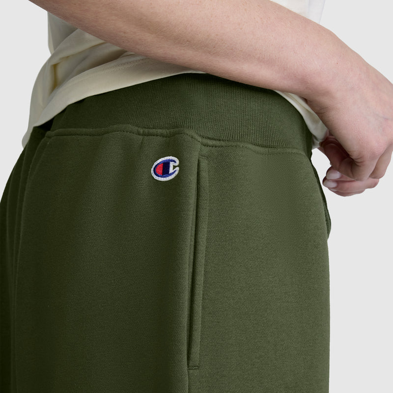 A person wears Champion Wide Leg Fleece Sweatpants with a C logo near the pocket, paired with a light-colored shirt.