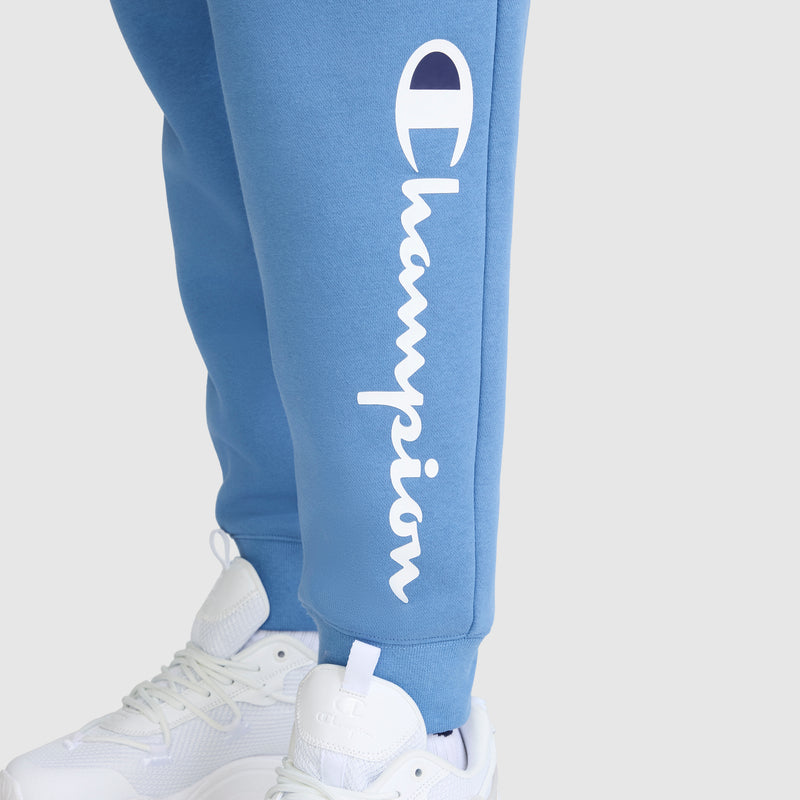 Lower legs in light blue Champion Powerblend Joggers, Classic Script Logo, featuring the white vertical Champion logo and paired with white sneakers—perfect fleece pants for women seeking comfort.