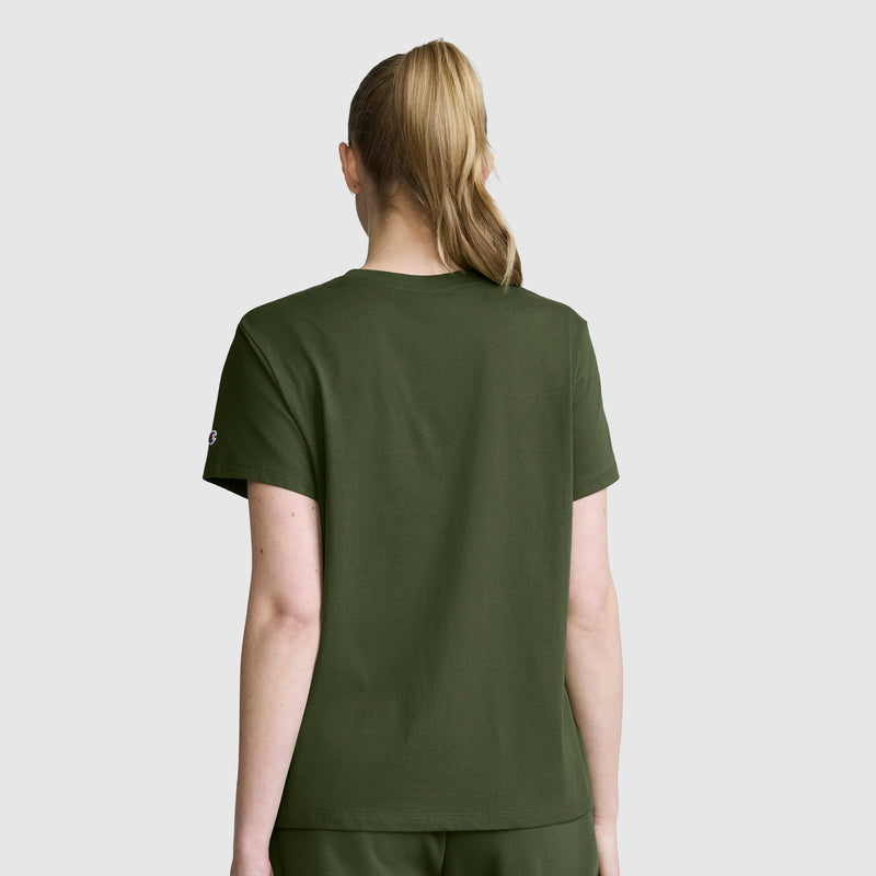 A person with blonde hair in a ponytail, wearing a Champion Classic T-Shirt with Script Logo in olive green and matching pants, is shown from the back against a plain light gray background.