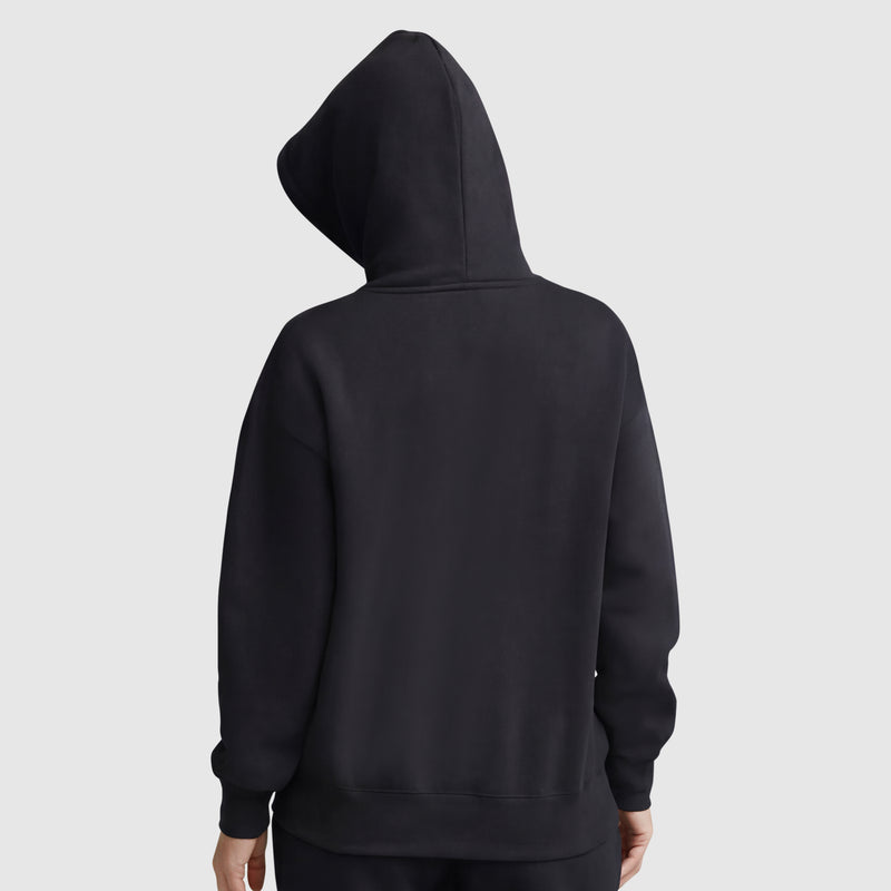 A person seen from the back, hood up, wearing a women’s Champion Tonal Script Freshman Powerblend Hoodie in plain black against a light gray background. The pullover shows no visible designs or logos.
