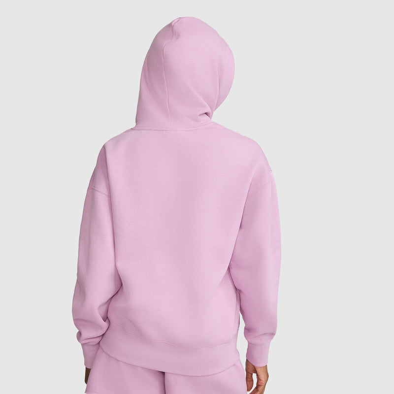A person is shown from the back, standing against a plain white background, wearing the Champion Tonal Script Freshman Powerblend Hoodie in light pink with matching pants.