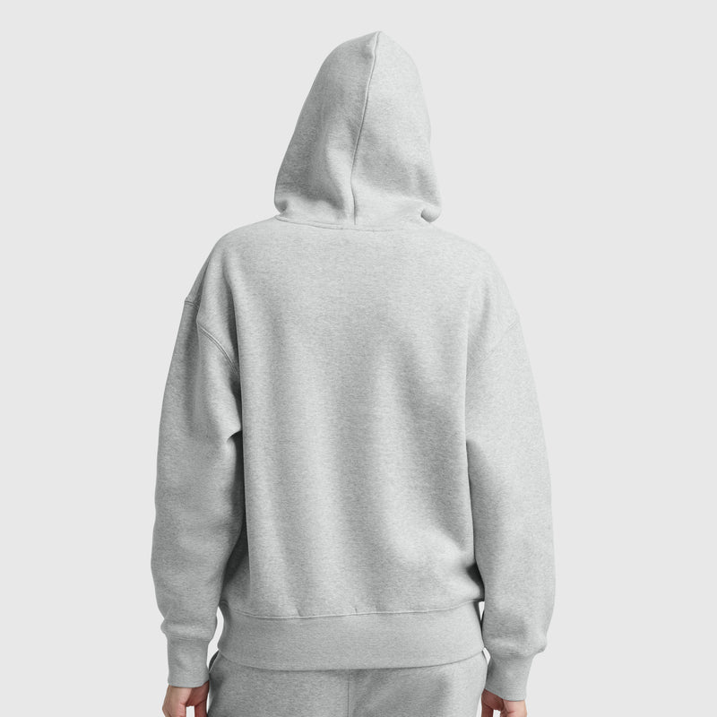 Person wearing a Champion Small C Freshman Powerblend Hoodie in light gray, featuring an adjustable drawcord hood and matching sweatpants. Seen from the back with the hood up against a white background. The midweight fleece ensures comfort and style.