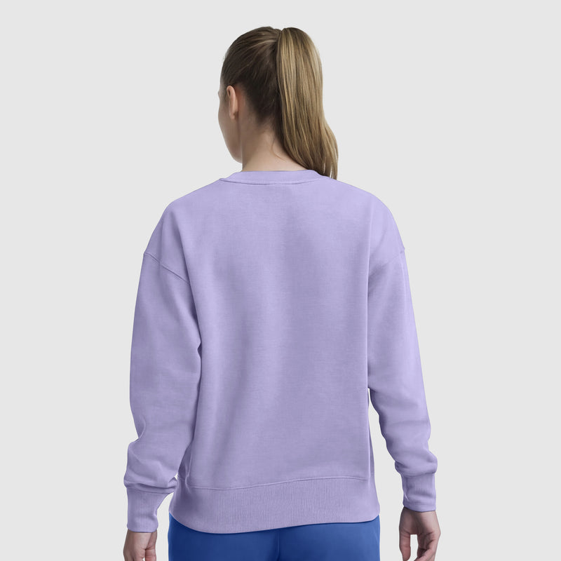 A person with long, light brown hair in a ponytail is shown from the back wearing a Champion Powerblend Crewneck, Small "C", in light purple and blue pants, standing against a plain background for everyday comfort.
