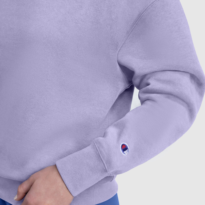 Someone wearing the Champion Powerblend Crewneck, featuring a small "C" logo and crafted from midweight fleece, stands against a plain background. Only their torso and one hand are visible, emphasizing this classic’s everyday comfort.