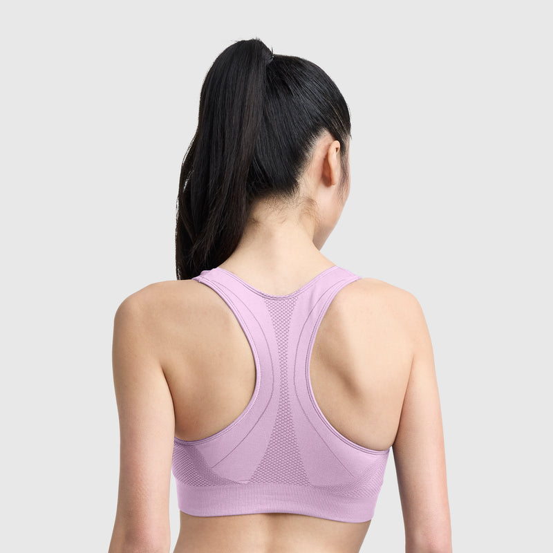 A woman with long black hair in a ponytail is shown from the back, wearing the Champion Seamless Racerback Sports Bra in light purple, which features moisture-wicking fabric and provides moderate support, set against a plain light gray background.
