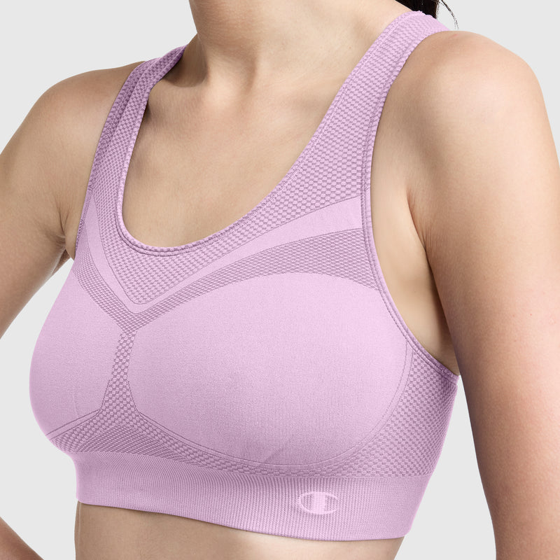 A woman models the Champion Seamless Racerback Sports Bra in light purple, featuring textured detailing and a racerback design for moderate support and moisture-wicking comfort; the image shows her from the shoulders to just below the bust against a plain background.