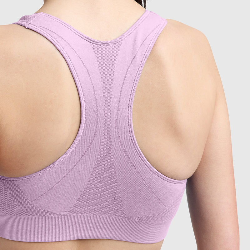 Close-up of a person’s upper back wearing the Champion Seamless Racerback Sports Bra in light purple, featuring moderate support and moisture-wicking properties, set against a plain, light gray background.