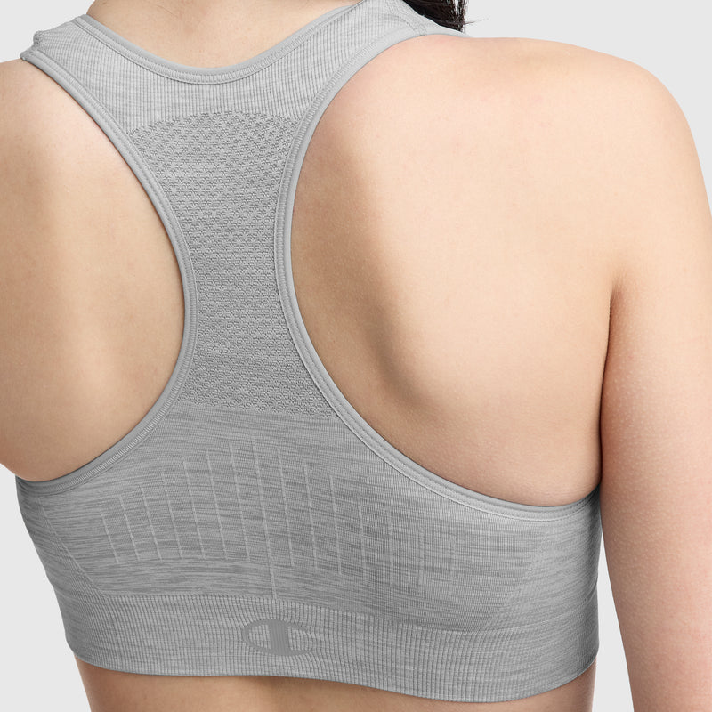 A close-up shows a person's back wearing the Champion Infinity Racerback Sports Bra, a light gray wireless style with textured mesh and subtle patterns for ventilation and support.