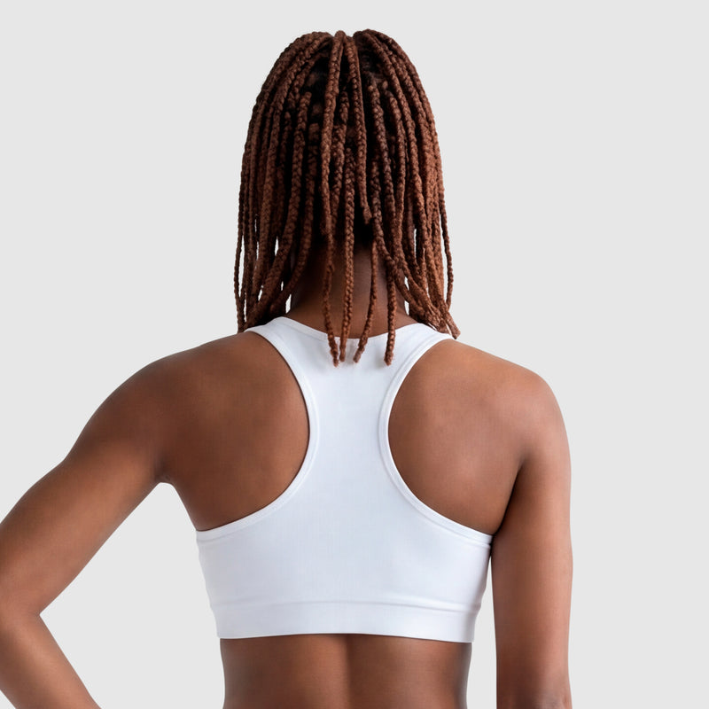 A person with long, brown box braids is shown from behind wearing the Champion Sports Bra, Script Logo in white cotton-spandex jersey against a plain light gray background.