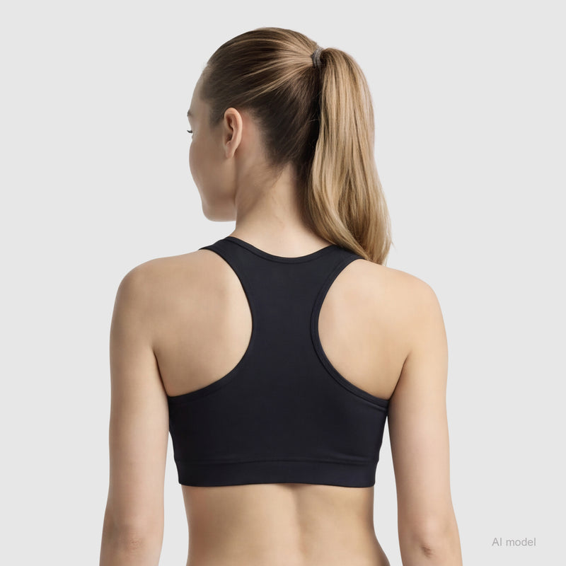 A woman with long blonde hair in a ponytail is shown from the back, wearing a black Champion Sports Bra with Script Logo, made of soft cotton-spandex jersey, against a plain light background.