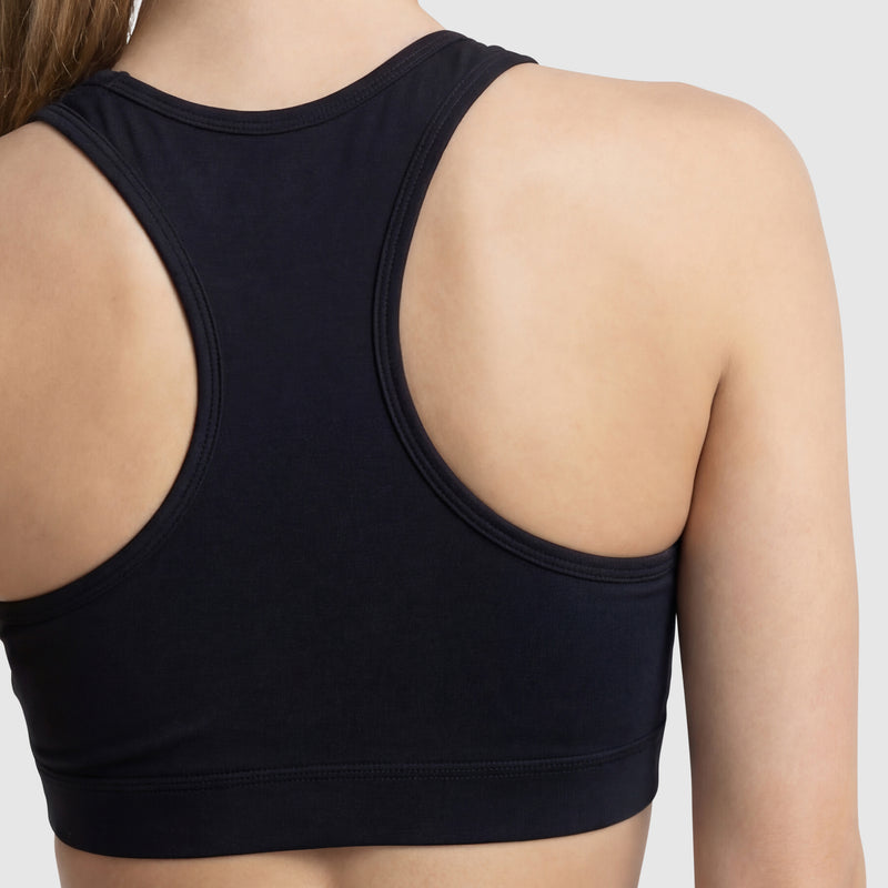 A close-up of a person’s upper back and shoulders wearing the Champion Sports Bra, Script Logo in black cotton-spandex jersey against a plain light background.