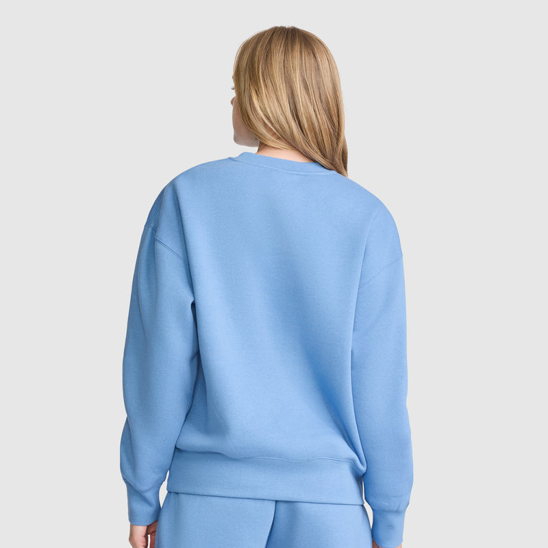 A person with long blonde hair, shown from the back against a plain light background, is wearing the Champion Powerblend Crewneck Sweatshirt, Script Logo, along with matching pants.