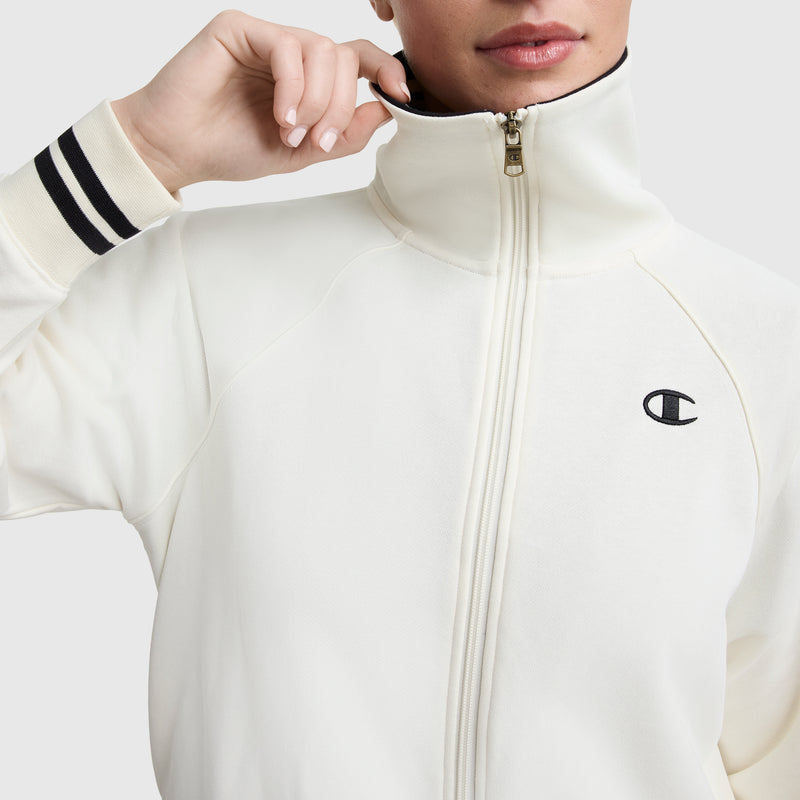 A person wearing the Champion Pitcher Full-Zip Mockneck Top with black striped cuffs and chest C Logo, holding the collar near their face.