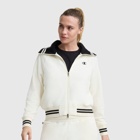 A woman with blonde hair in a ponytail wears the Champion Pitcher Full-Zip Mockneck Top, featuring a black collar, striped cuffs, soft French terry fabric, and a small C Logo on the left chest. She stands against a plain light gray background.