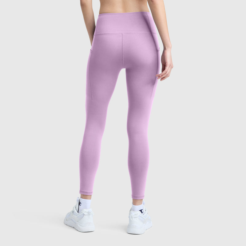 A person wearing light purple Champion C Logo high-waisted silky soft leggings and white sneakers stands facing away on a plain light gray background.