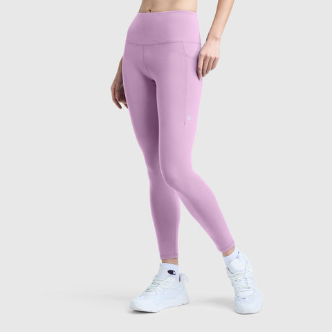 A person is shown from the waist down wearing Champion C Logo high-waisted, light purple silky soft leggings and white athletic shoes, standing against a plain light gray background.