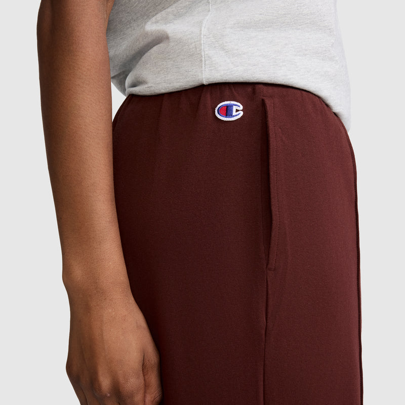 Sporting a gray shirt and maroon Champion Open Bottom Pant, styled athletically with the iconic Champion logo visible on the waistband, this look perfectly highlights the comfort and sporty appeal of the Champion brand.