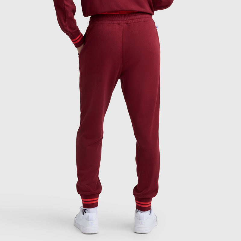 A person wearing Champion Pitcher Pant, C Logo joggers stands with their back to the camera against a plain light background.
