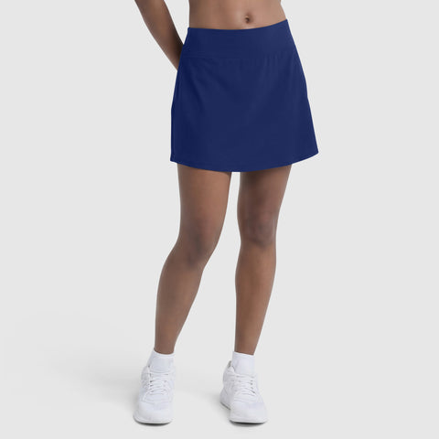 Model wears the Champion Courtside Skort, C Logo in royal blue, paired with white socks and sneakers. Only the lower half is visible against a plain white background, highlighting effortless court style.