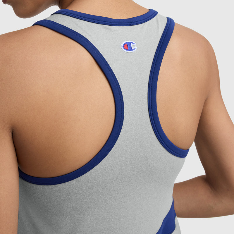 Close-up of a person’s upper back wearing the Champion Match Point Tennis Dress with an embroidered script logo, featuring a gray racerback design and blue trim, standing against a plain light background.