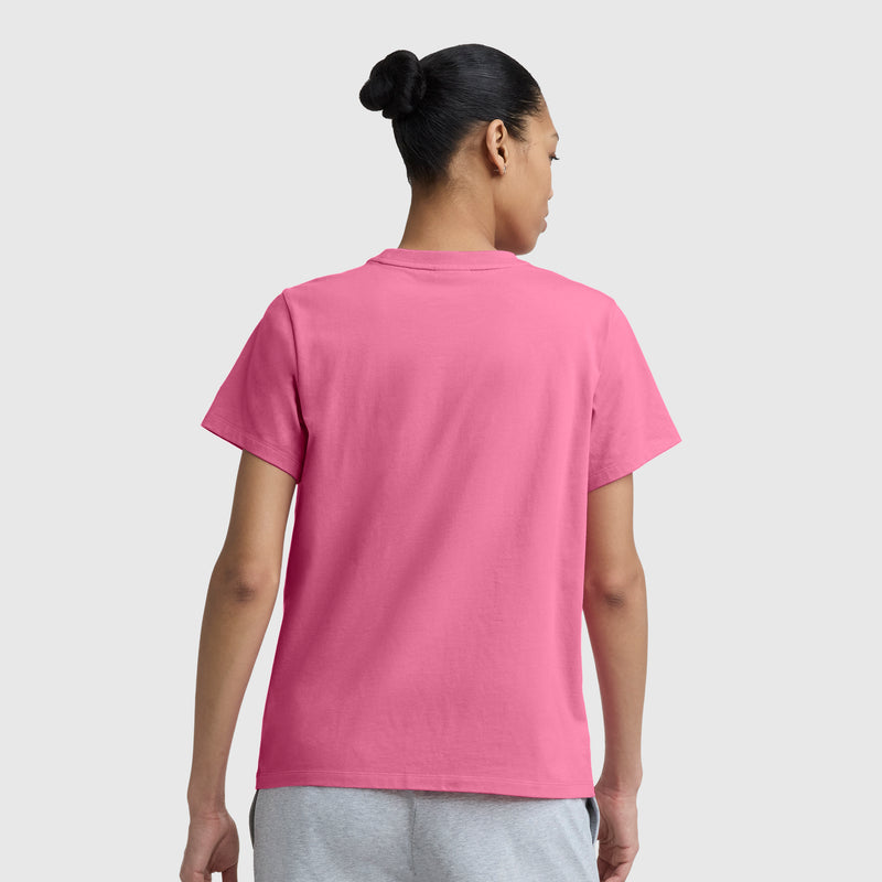 Person with dark hair in a bun wears a Champion Painted Bouquet Graphic T-Shirt, C Logo in pink and light gray shorts, standing with their back to the camera against a plain light gray background.