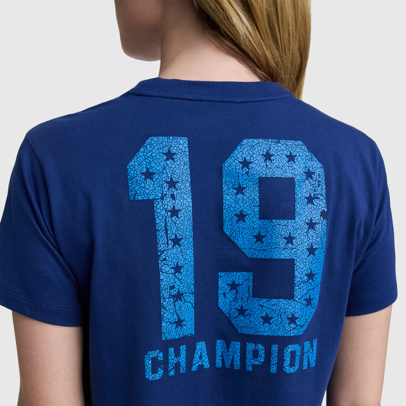 A person wearing the Champion Grid Iron '19 Graphic T-Shirt, featuring a bold number 19 and C logo on the back with star patterns, creates a sport-inspired look.