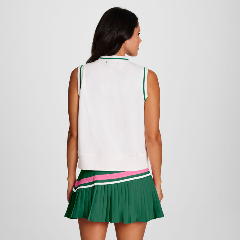 A woman with long dark hair, seen from behind, wears the Champion Country Club Sleeveless Top with an embroidered script logo and a green pleated skirt with pink and white stripes near the hem, standing against a light background.