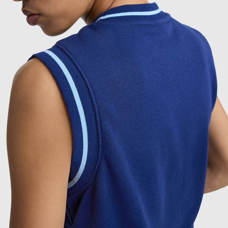Wearing the Champion Country Club Sleeveless Top (Embroidered Script Logo) in a women’s standard fit, this person sports a blue sleeveless design with light blue and white armhole stripes—shown from behind with shoulder, upper back, and partial face visible.